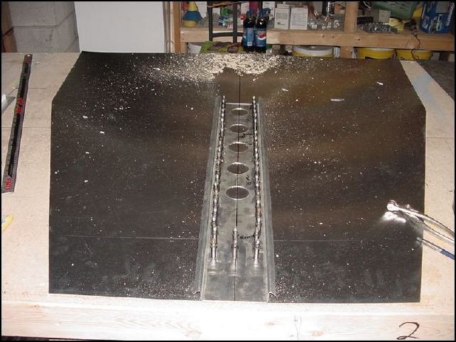 Drill and cleco the stiffener to the floor skin.   NOTE: this image also shows two rows of three holes each at the front (bottom of the picture).  These holes are for the forward floor channel.  Normally you woud not drill these holes at this time but the skin sent to me with the kit was pre-punched at the factory so I had drilled these holes the first time I tried to put this sub-assembly together.  The reason I have started this assembly over is because the skin sent from Zenair was not drilled correctly for the longerons.  I could have used it I guess, but then my longerons would have been 5mm off and this really bothered me so I cut a new floor skin.