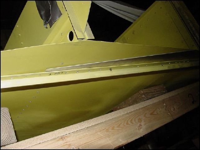 Position 20-F-24-5 (lower longeron doubler) between the bottom skin of the fuselage and the longeron.  The front of this doubler is about three rivet holes in front of the rear of the front channel.  The rear of this doubler is just a few mm behind the rear channel, and the side of this part is even with the side of the fuselage.  You will need to trim this part to fit flush starting about 350 mm from the tail end of it.