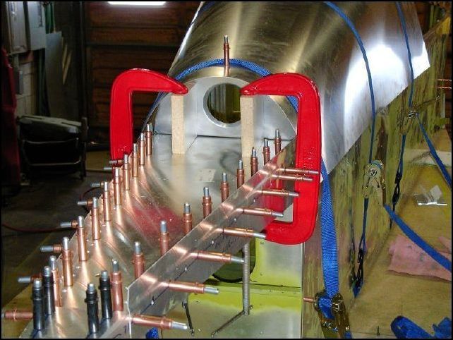 Cut two blocks of wood to 81 degree angles and clamp them to the rear of the fuselage.  This was the easy way to make sure that the rear bulkhead was set to a 9 degree tilt back.  I then put straps around the rear skin and pulled the skin around the bulkheads, but not too tight yet.