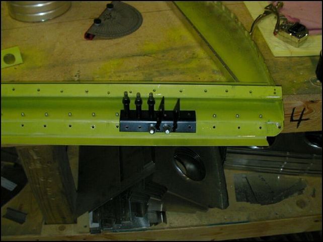 Position the right pivoting bracket to the bottom of the baggage area bulk head 152 mm from the side skin area.  Drill and cleco for A5 rivets.