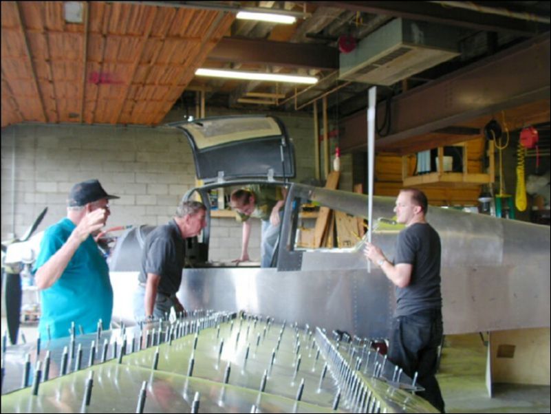 Deburr, clean, prime, and rivet the flap to the wing.  Deburr, clean, and prime all top skins.  Trim inboard skin to fit the shape of the fuselage.  Drill holes in side of fuselage for wires, pitot, static, and control cables.  Bolt wing to aircraft!