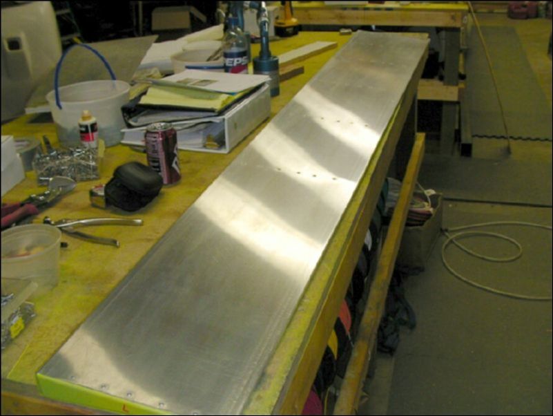 Rivet the bottom of the flap skin to the ribs.