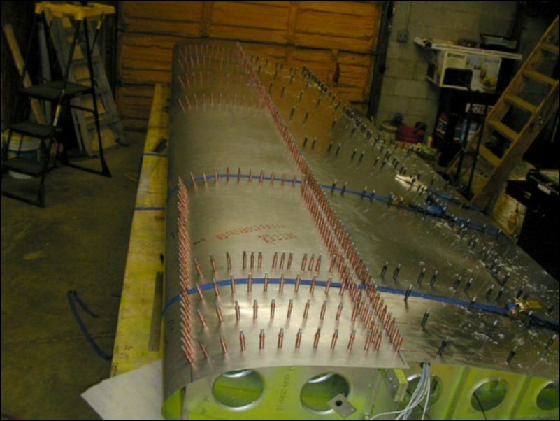 Pull top front skins over wing with straps then drill and cleco skins.