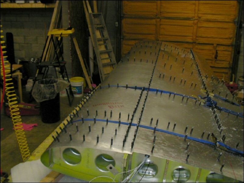 Pull top front skins over wing with straps then drill and cleco skins.