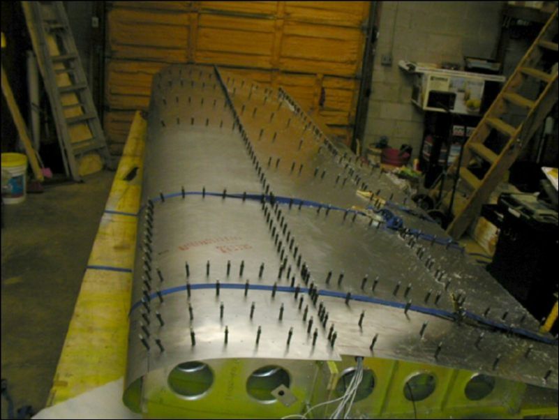 Pull top front skins over wing with straps then drill and cleco skins.